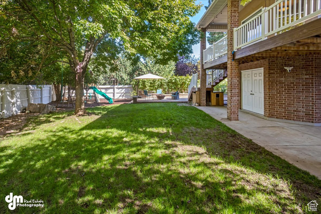 View of yard featuring a playground, a deck, and a patio