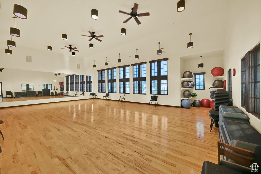 Workout area featuring ceiling fan, a towering ceiling, and light hardwood / wood-style floors