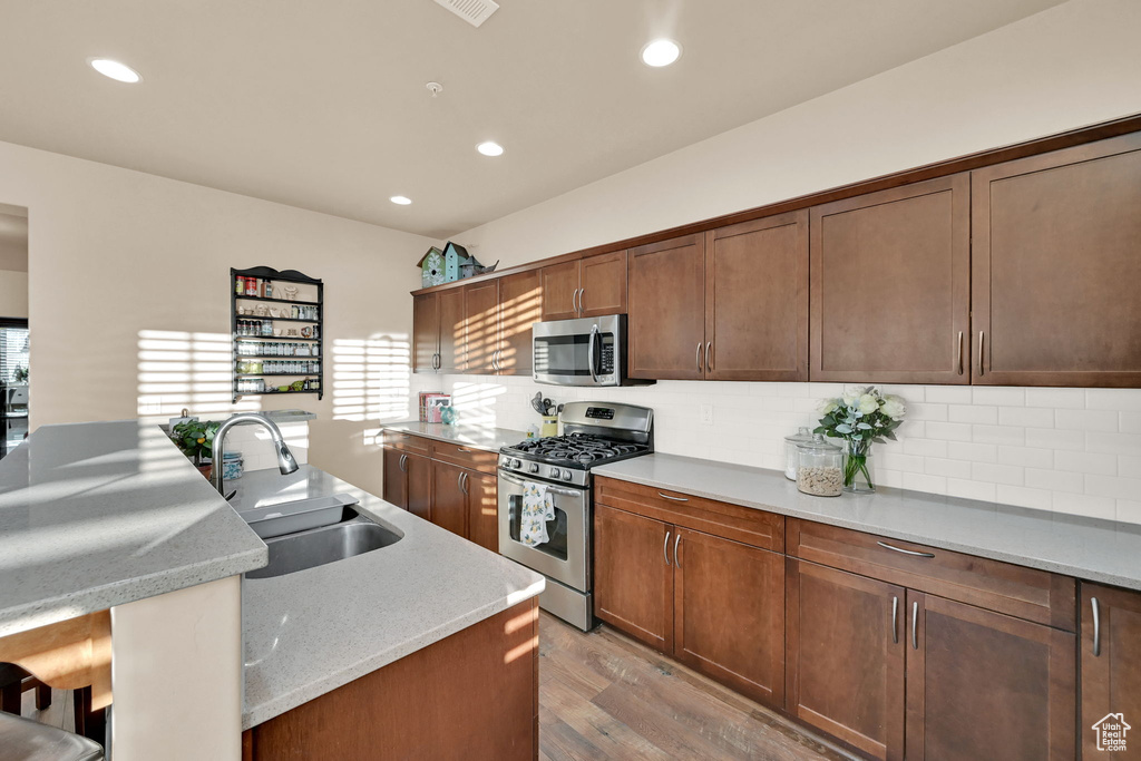 Kitchen featuring a center island, tasteful backsplash, sink, light hardwood / wood-style flooring, and appliances with stainless steel finishes