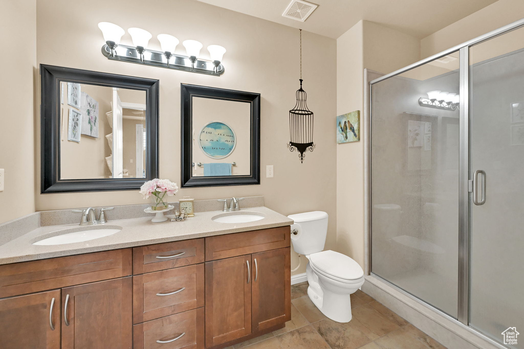 Bathroom featuring a shower with door, vanity, and toilet