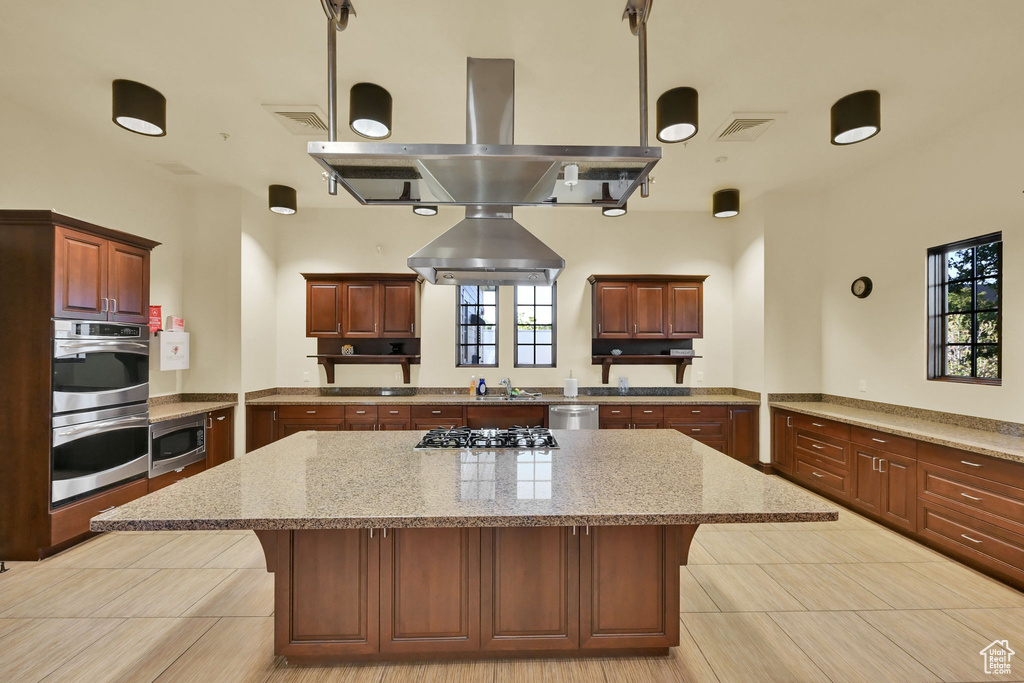 Kitchen with a breakfast bar, kitchen peninsula, a kitchen island, island range hood, and stainless steel appliances