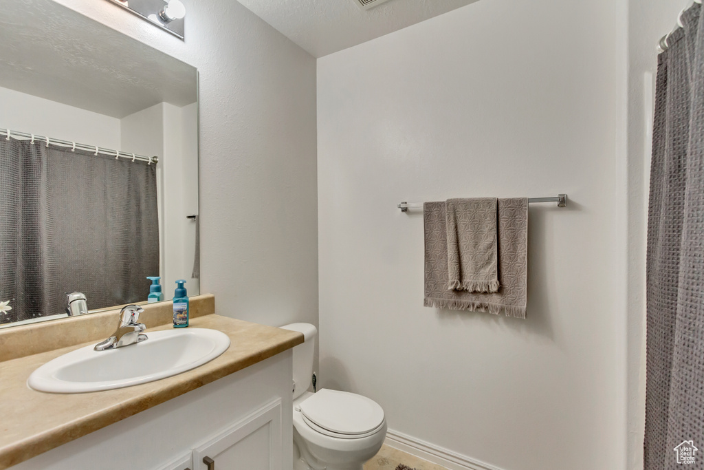 Bathroom featuring a textured ceiling, vanity, and toilet