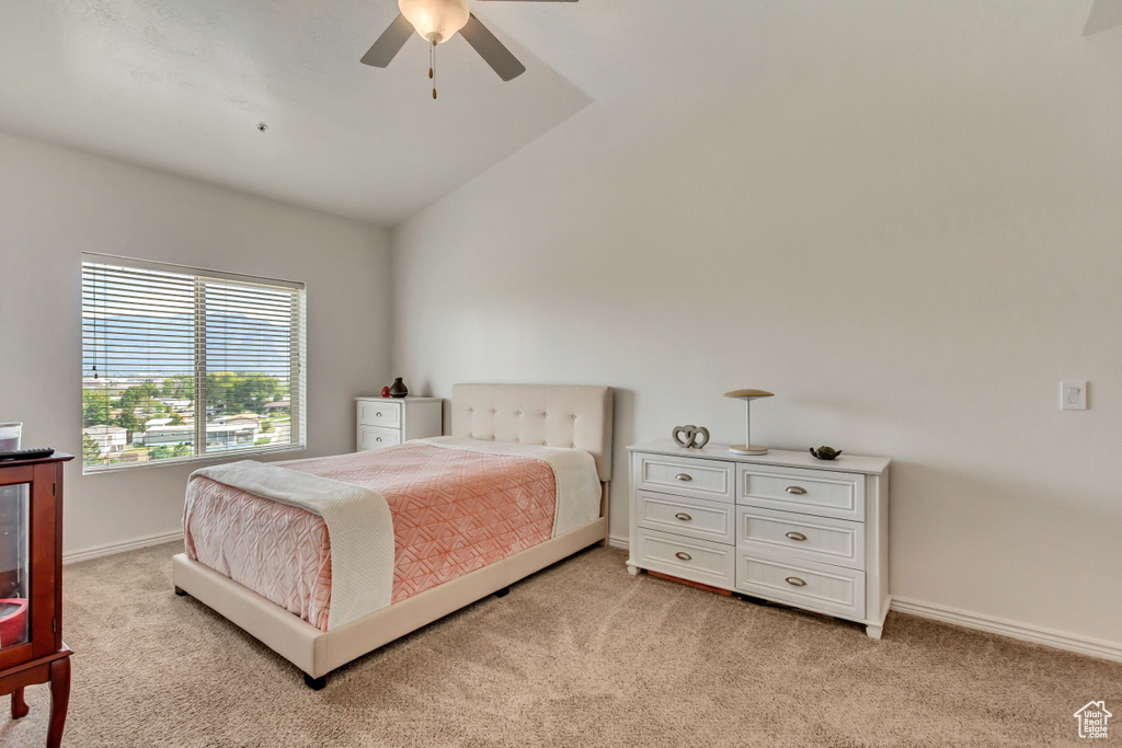 Carpeted bedroom featuring vaulted ceiling and ceiling fan