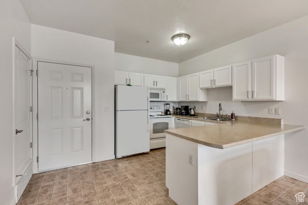 Kitchen with white appliances, sink, kitchen peninsula, and white cabinets