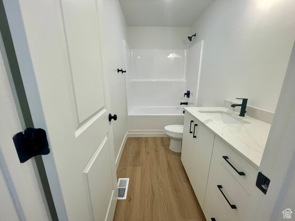 Full bathroom with vanity, toilet, hardwood / wood-style flooring, and shower / washtub combination