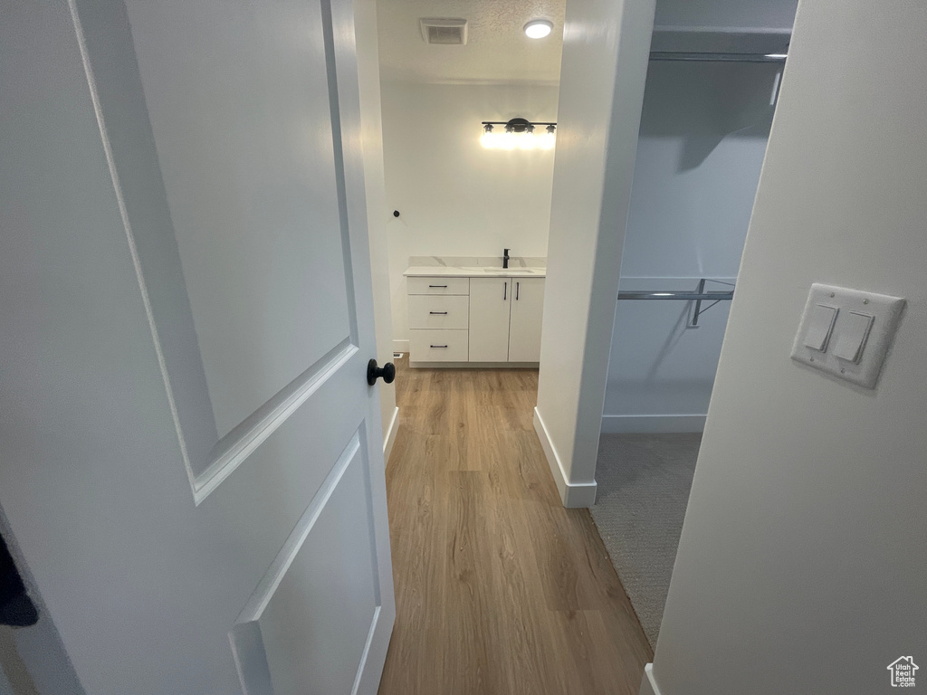 Hall with sink, light hardwood / wood-style flooring, and a textured ceiling