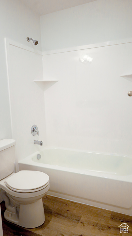 Bathroom featuring shower / bathing tub combination, hardwood / wood-style flooring, and toilet