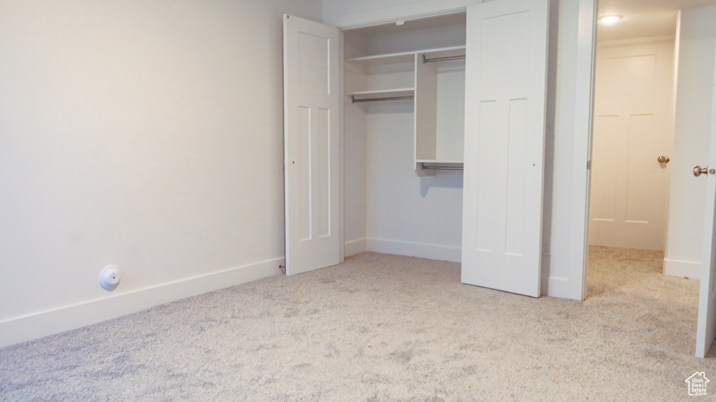 Unfurnished bedroom featuring light carpet and a closet