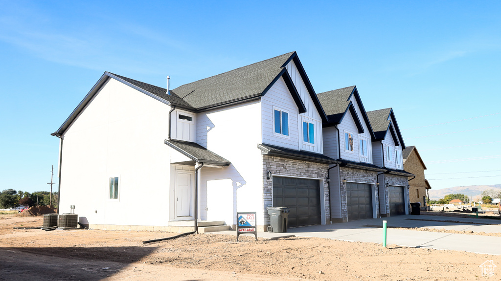 Back of house featuring central AC unit and a garage