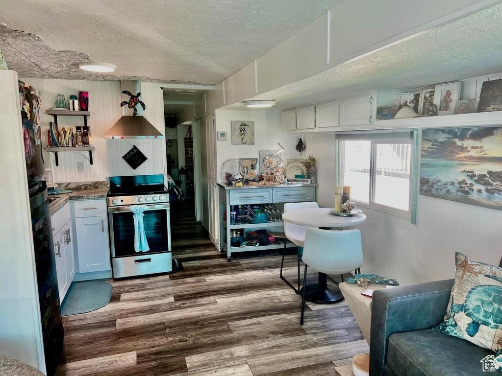 Kitchen featuring stainless steel stove, a textured ceiling, white cabinetry, and dark wood-type flooring