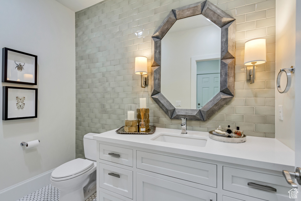 Bathroom with backsplash, tile patterned flooring, vanity, and toilet