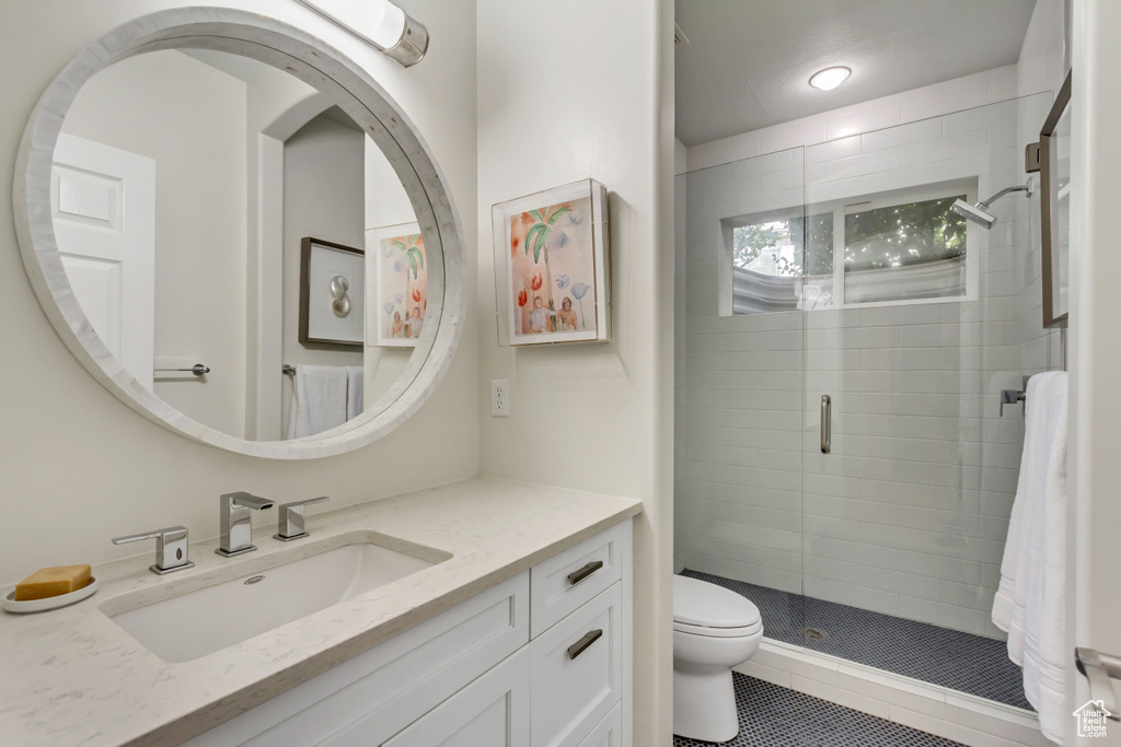 Bathroom featuring vanity, a shower with shower door, toilet, and tile patterned flooring