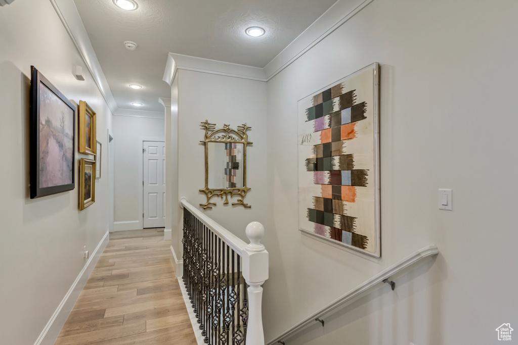 Corridor with light hardwood / wood-style flooring and crown molding