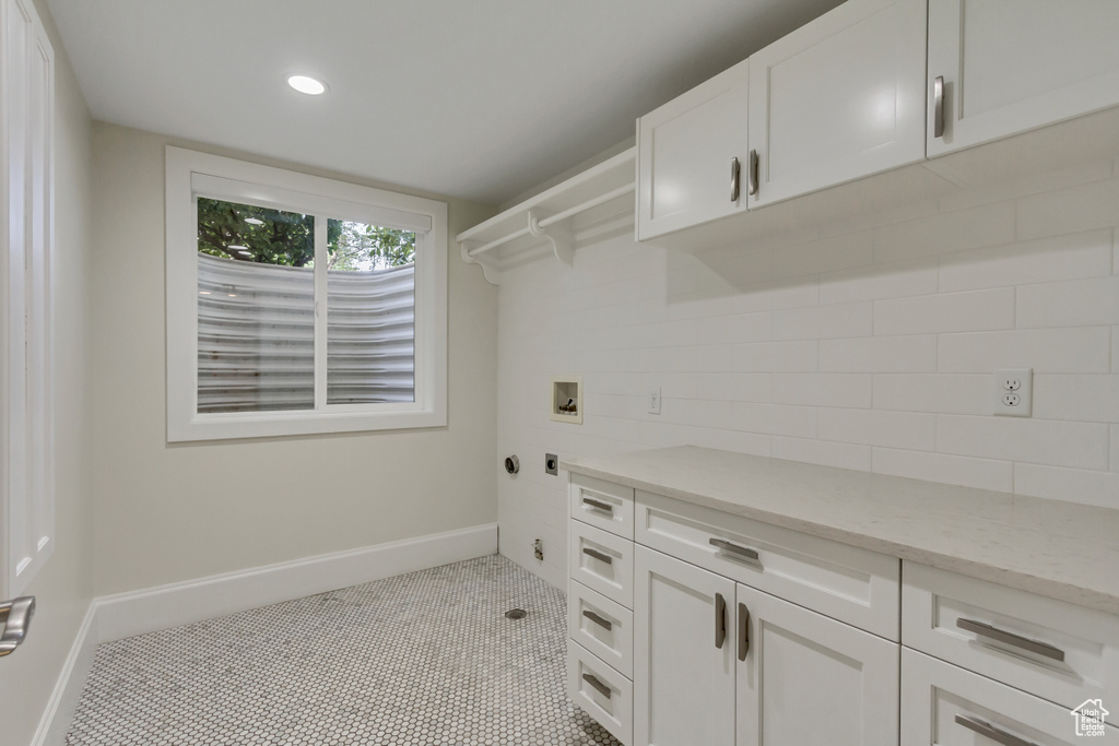 Laundry room with cabinets, hookup for a washing machine, and light tile patterned flooring