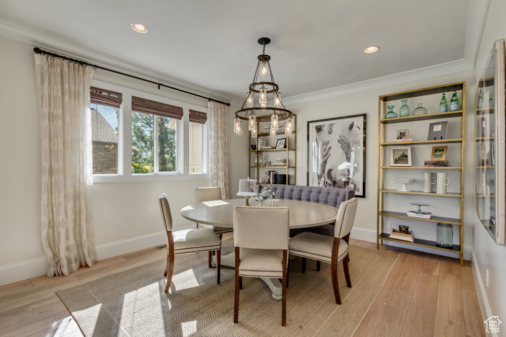 Dining area with ornamental molding, a chandelier, and light hardwood / wood-style floors