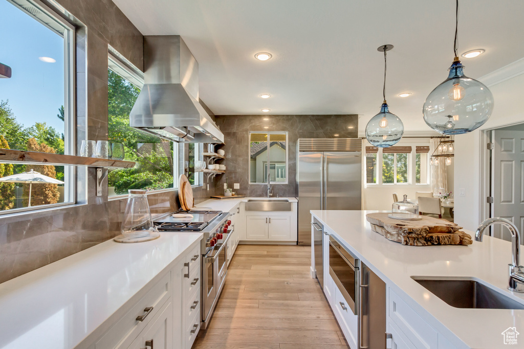 Kitchen featuring pendant lighting, sink, white cabinetry, extractor fan, and high quality appliances