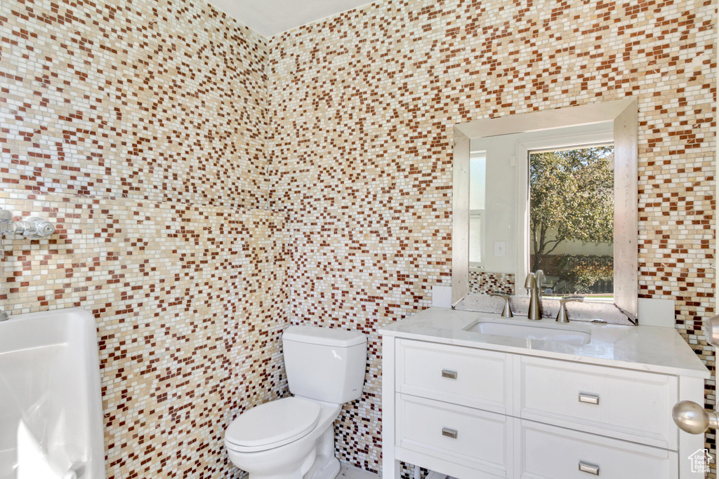 Bathroom featuring tile walls, vanity, and toilet