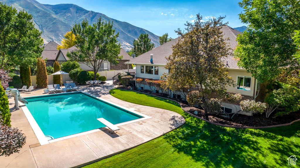 View of swimming pool with a lawn, a mountain view, a patio area, and a diving board