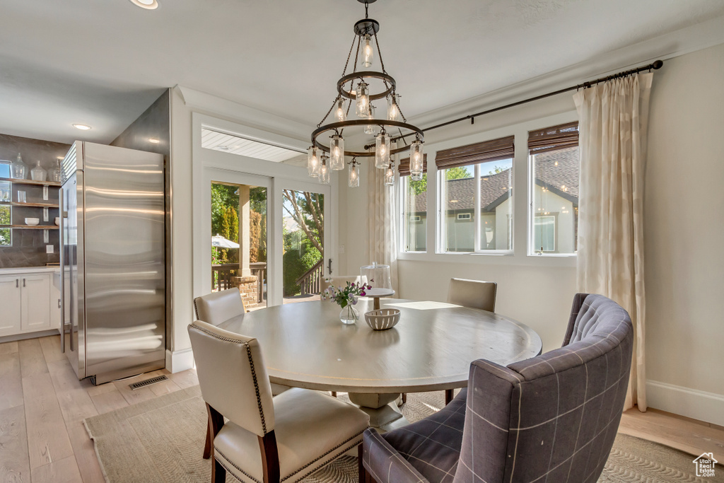 Dining area featuring a notable chandelier, light hardwood / wood-style flooring, and plenty of natural light