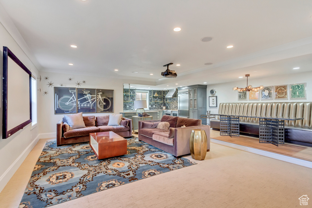 Living room featuring light colored carpet, a chandelier, and ornamental molding