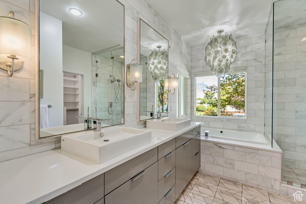 Bathroom with shower with separate bathtub, vanity, and a chandelier