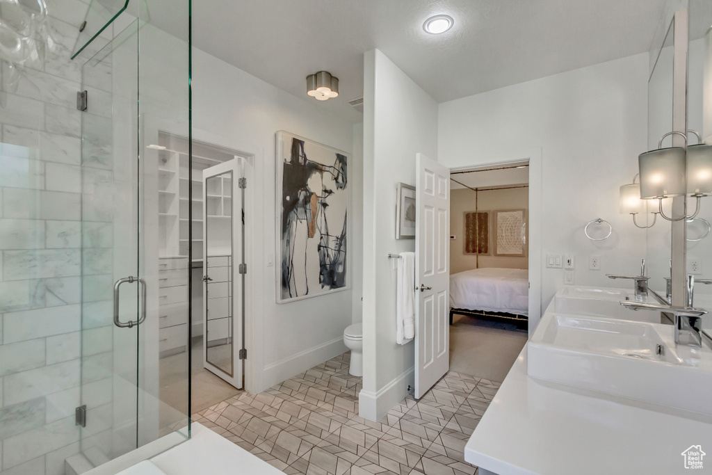 Bathroom featuring vanity, a shower with shower door, toilet, and tile patterned flooring