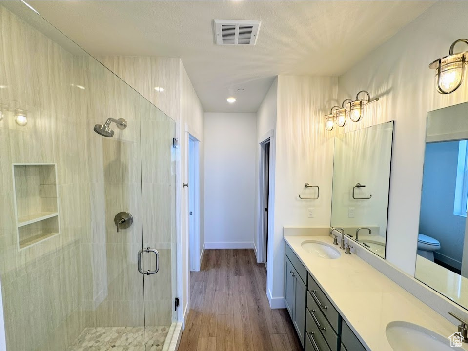 Bathroom featuring toilet, vanity, hardwood / wood-style floors, and an enclosed shower