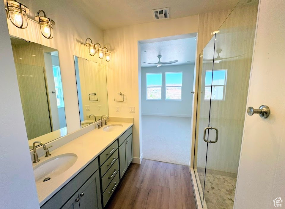 Bathroom featuring ceiling fan, hardwood / wood-style flooring, walk in shower, and vanity