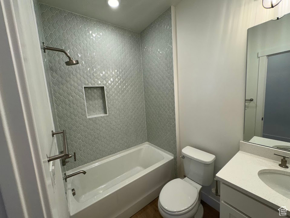 Full bathroom with tiled shower / bath combo, vanity, and toilet