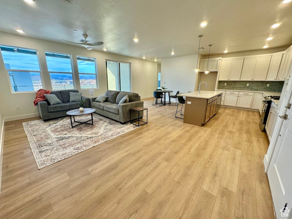 Living room with ceiling fan, light hardwood / wood-style flooring, and sink