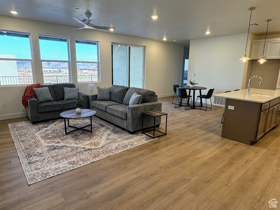 Living room with ceiling fan, light wood-type flooring, and sink