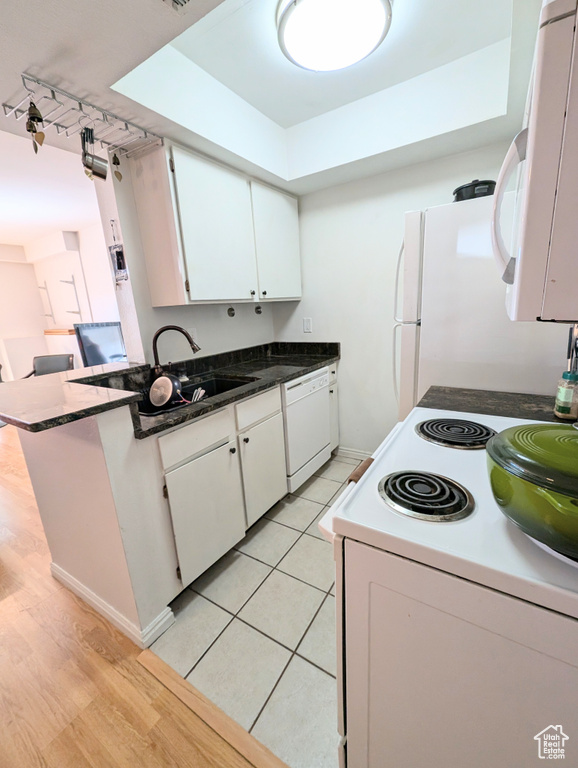 Kitchen with white appliances, sink, light hardwood / wood-style flooring, and white cabinets