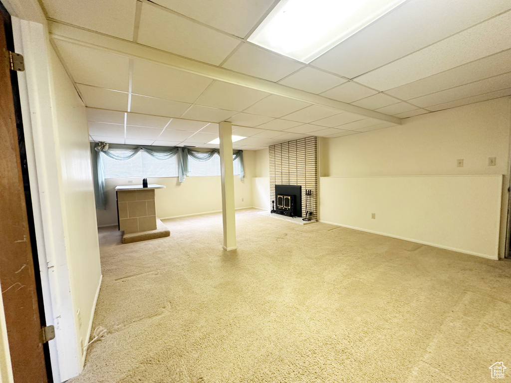 Basement with a drop ceiling, carpet flooring, and a fireplace