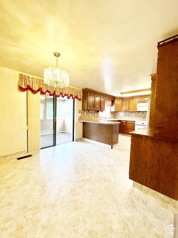 Kitchen with light carpet, an inviting chandelier, hanging light fixtures, and decorative backsplash