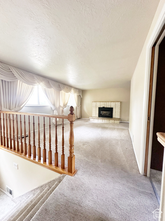 Hall featuring light carpet and a textured ceiling