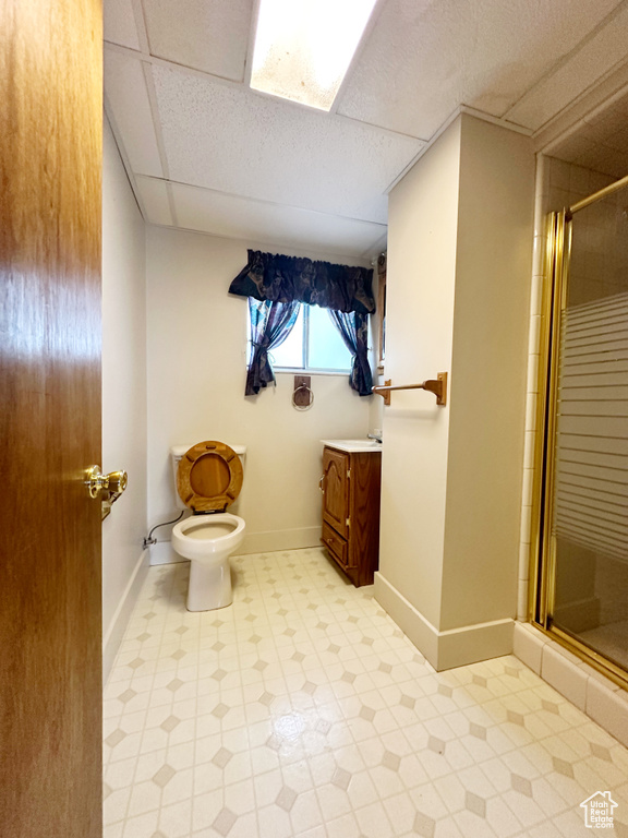 Bathroom featuring walk in shower, a drop ceiling, vanity, and toilet