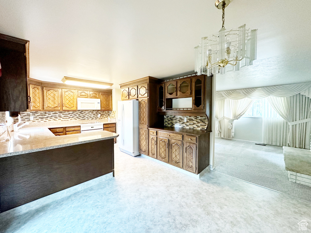 Kitchen featuring decorative backsplash, white appliances, light colored carpet, and an inviting chandelier