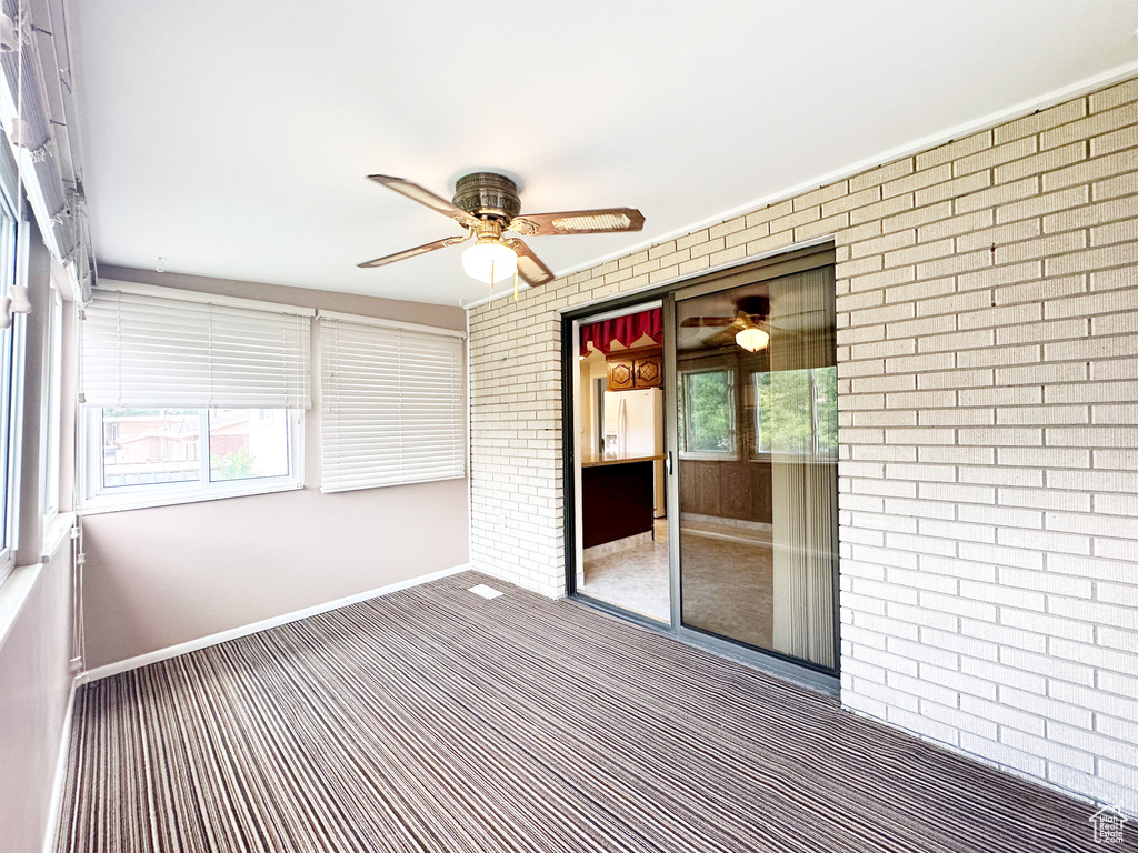 Unfurnished sunroom featuring a healthy amount of sunlight and ceiling fan