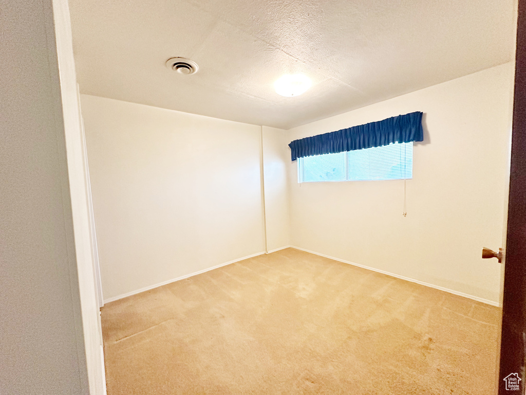 Unfurnished room with a textured ceiling and carpet flooring