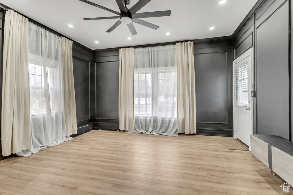 Unfurnished room featuring crown molding, light hardwood / wood-style flooring, ceiling fan, and a wealth of natural light