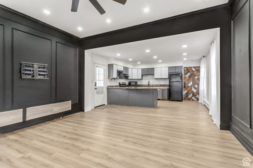 Kitchen with ceiling fan, light hardwood / wood-style floors, crown molding, and black refrigerator