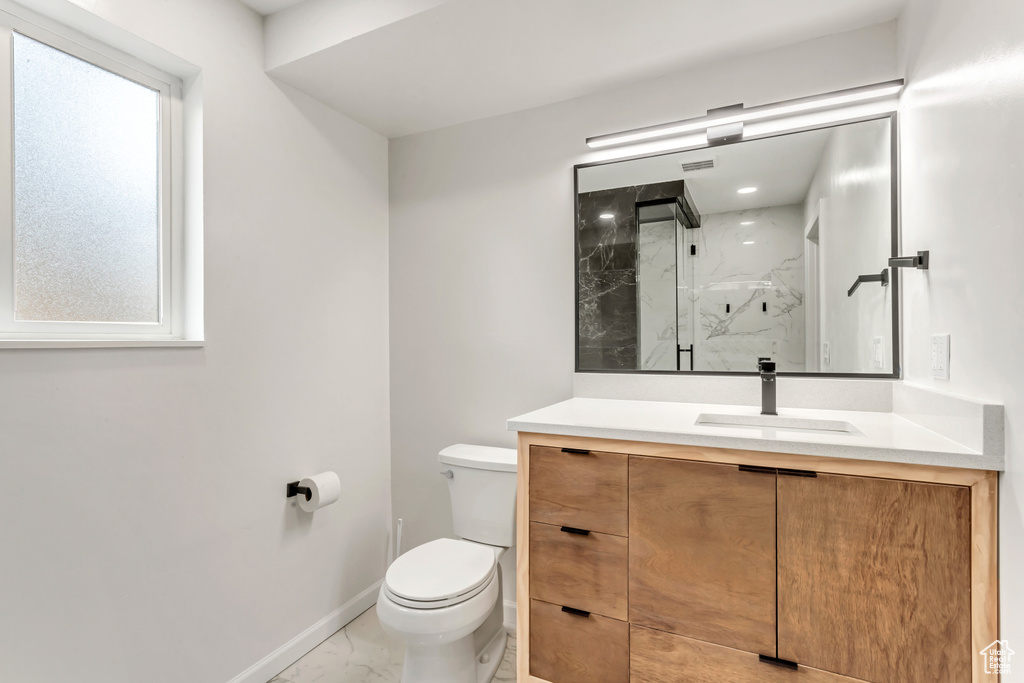 Bathroom featuring vanity, toilet, and a shower with door