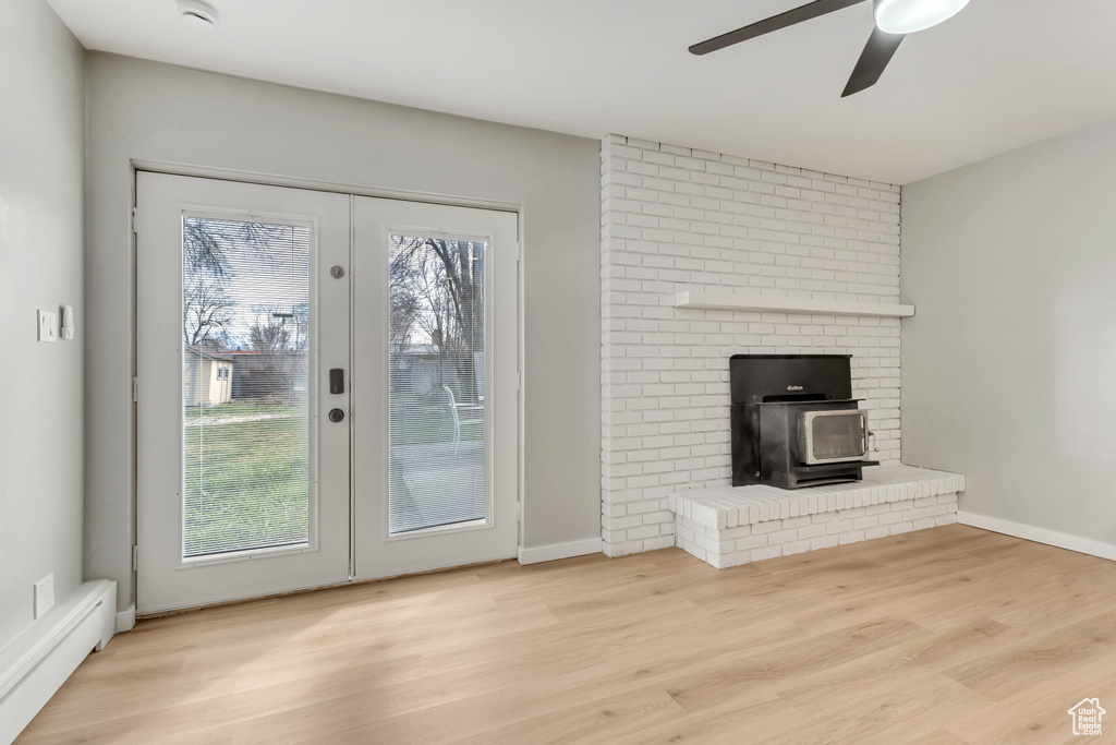 Doorway to outside featuring a brick fireplace, ceiling fan, plenty of natural light, and light wood-type flooring