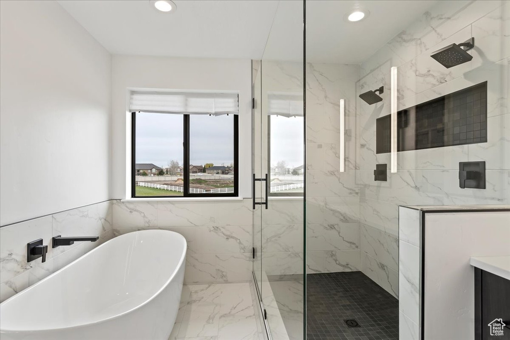 Bathroom featuring vanity, tile walls, and shower with separate bathtub