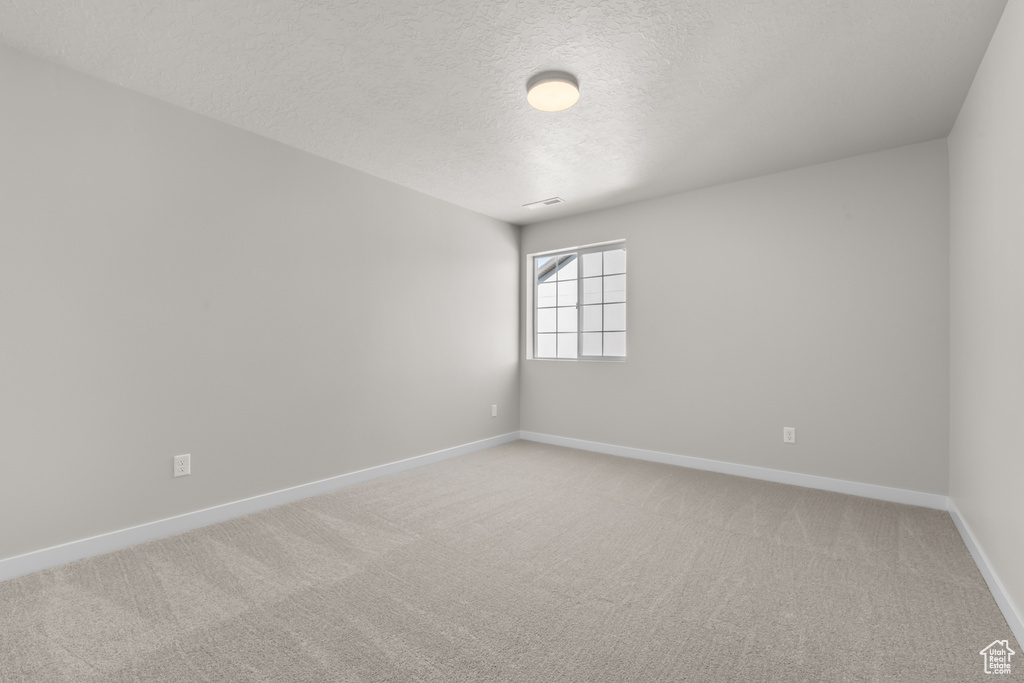 Spare room featuring a textured ceiling and carpet floors