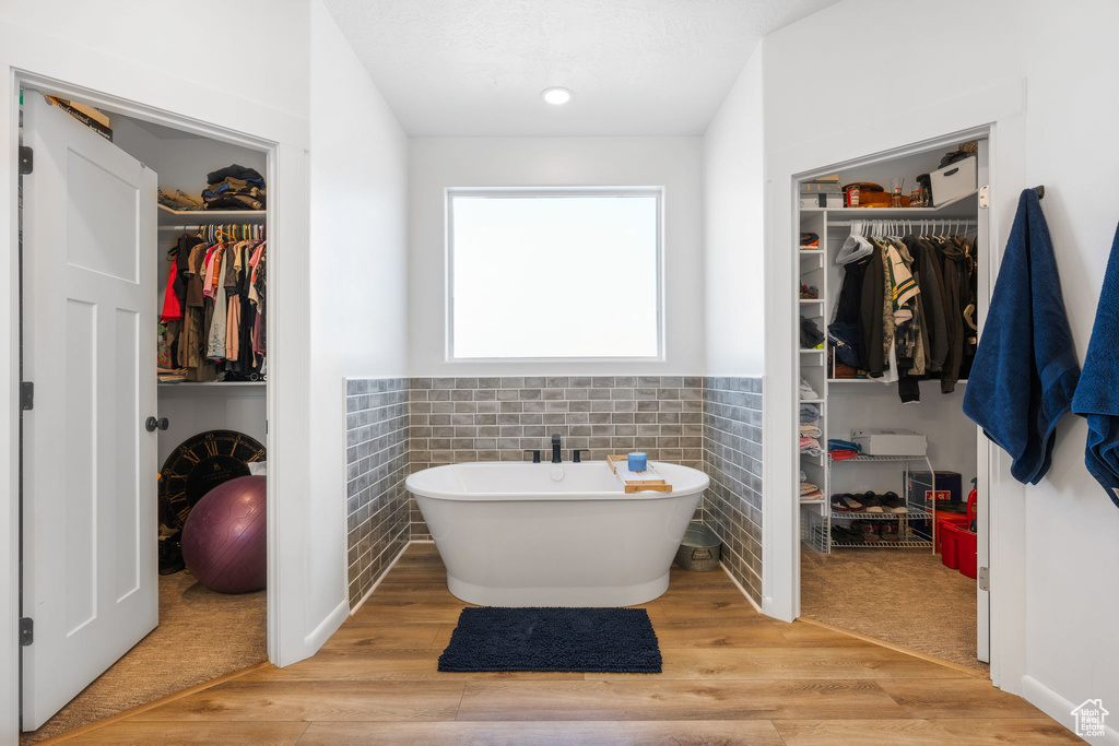 Bathroom with tile walls, a bath, and hardwood / wood-style floors