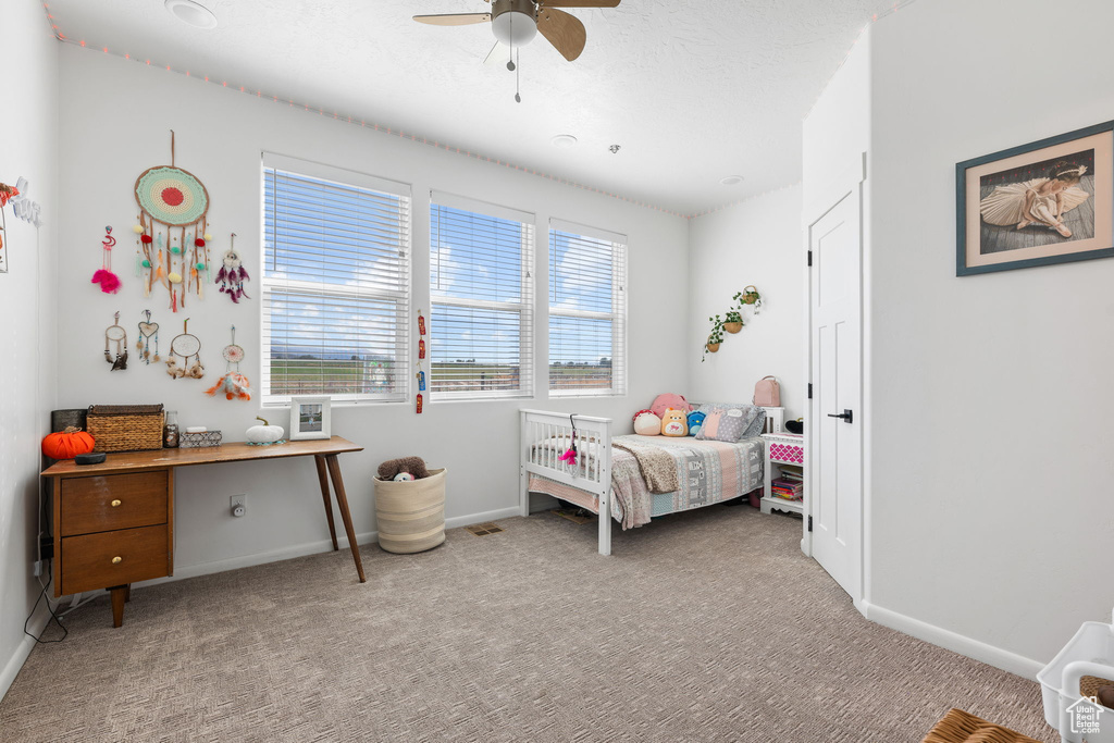 Bedroom with ceiling fan, light colored carpet, and multiple windows