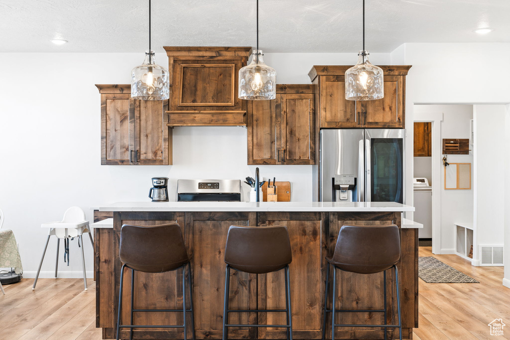 Kitchen with light hardwood / wood-style floors, a kitchen bar, and stainless steel appliances