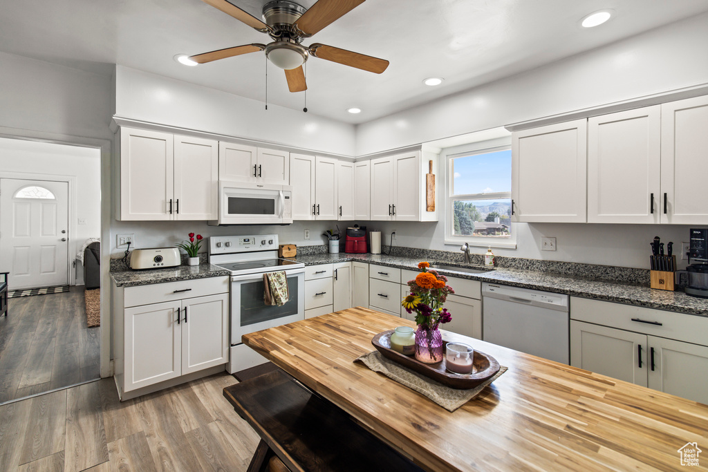 Kitchen with sink, white cabinetry, white appliances, hardwood / wood-style floors, and ceiling fan