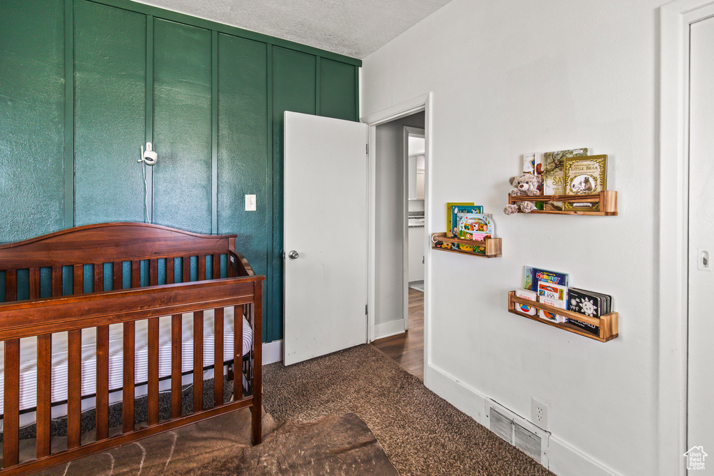 Carpeted bedroom with a textured ceiling and a nursery area